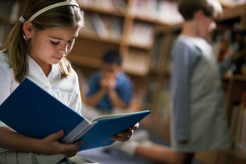 A photo of a girl reading a book in the library