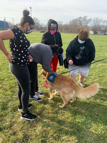 a photo showing a few children playing with a therapy dog